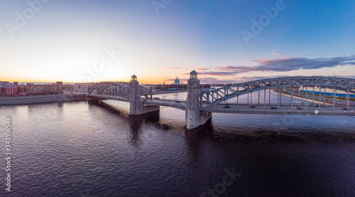St. Petersburg Russia. Aerial panoramic view from drone to Peter the Great bridge of white nights. Bolsheokhtinsky bridge across the river Neva with evening lighting city with driving cars on highway.