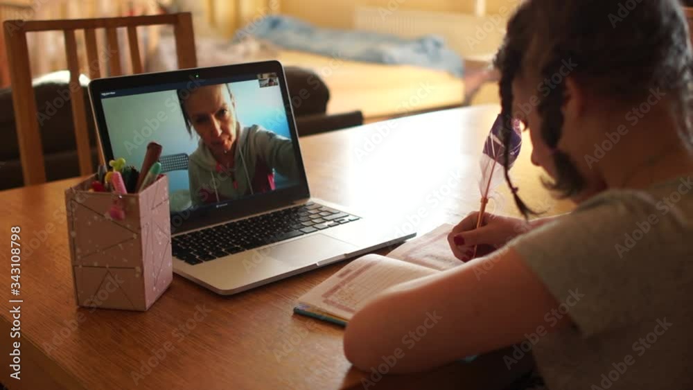 Cute schoolgirl with pigtails on her head has a remote lesson with her teacher. Distance learning during quarantine coronovirus covid-19 Cute schoolgirl with pigtails on her head has a remote lesson with her teacher. Distance learning during quarantine coronovirus covid-19