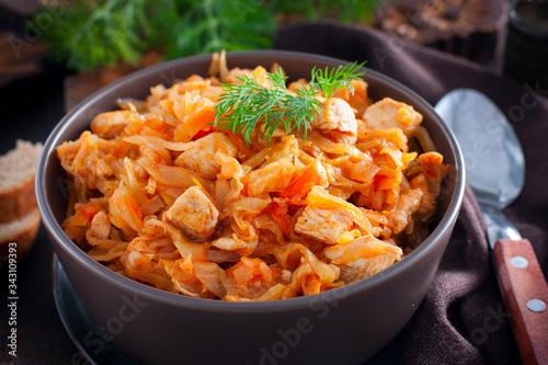 Braised cabbage with chicken breast in a clay bowl, selective focus