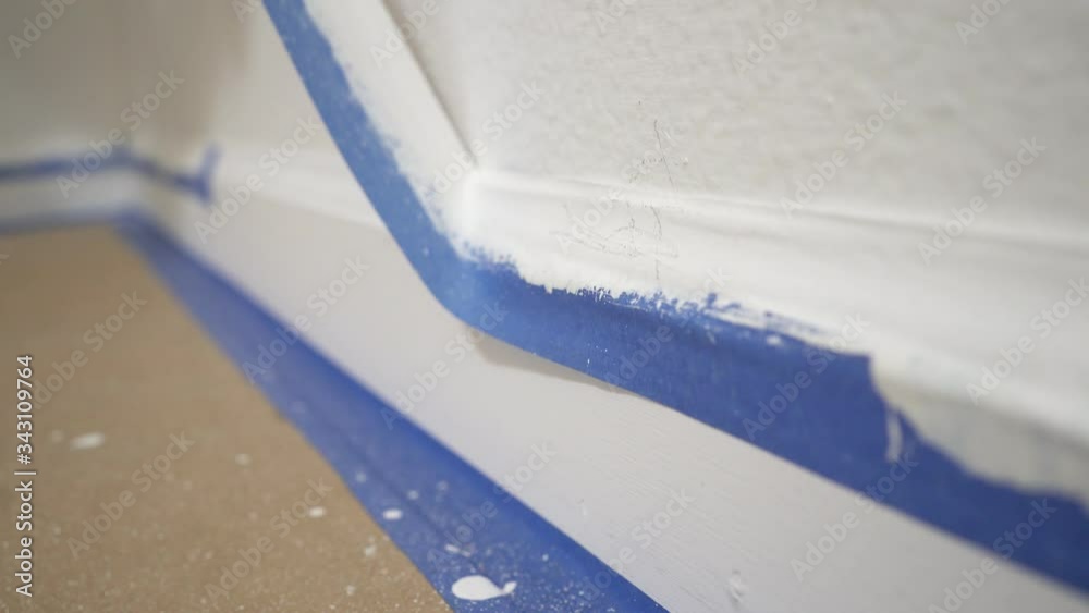 Removing masking tape from molding. A painter pulls of blue painter's