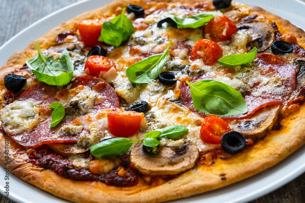 Pizza with pepperoni gorgonzola and champignons on wooden table
Pizza with pepperoni gorgonzola and champignons on wooden table