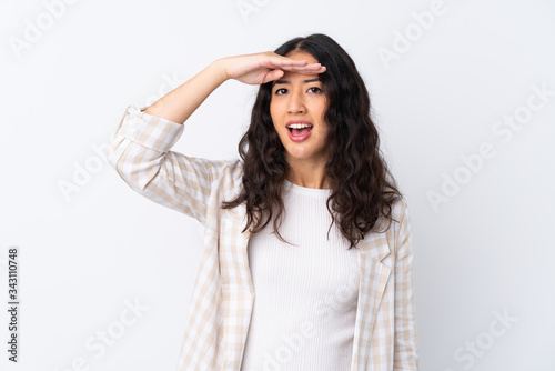 Mixed race woman over isolated white background looking far away with hand to look something
