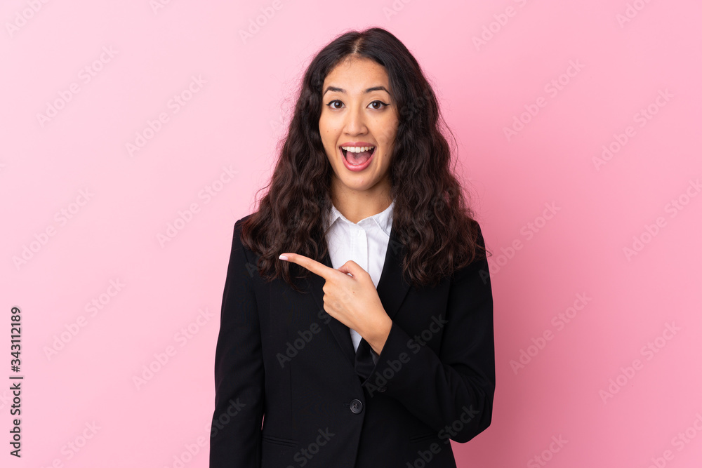Mixed race business woman over isolated pink background pointing finger to the side Mixed race business woman over isolated pink background pointing finger to the side