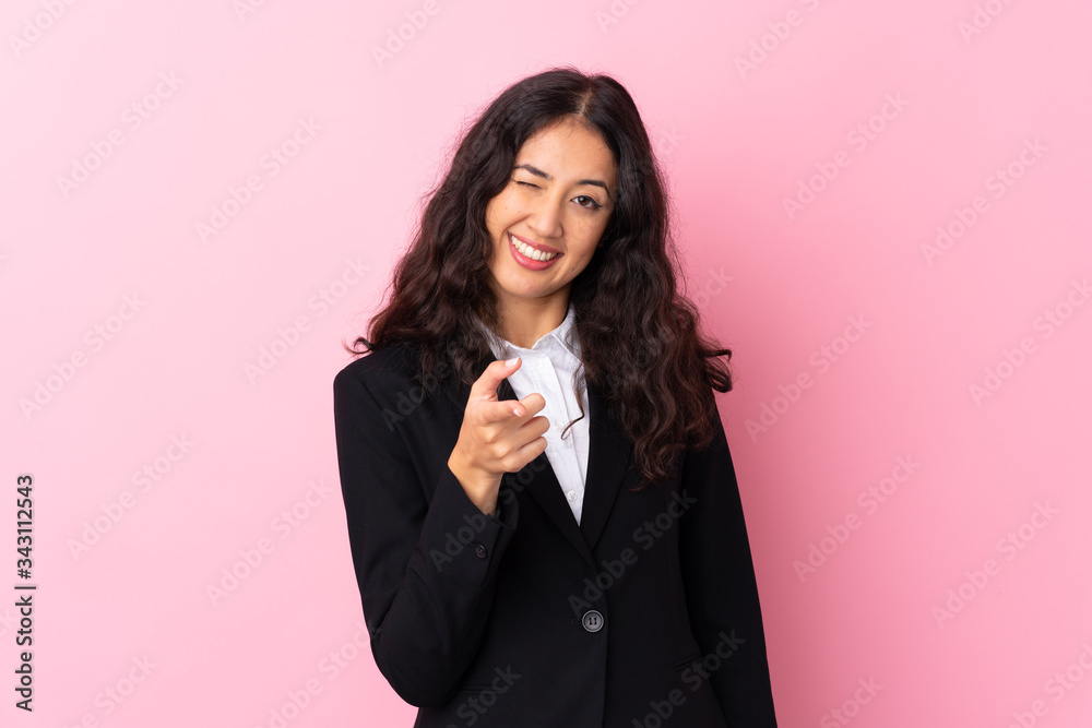 Mixed race business woman over isolated pink background points finger at you Mixed race business woman over isolated pink background points finger at you