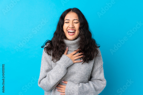 Spanish Chinese woman over isolated blue background smiling a lot