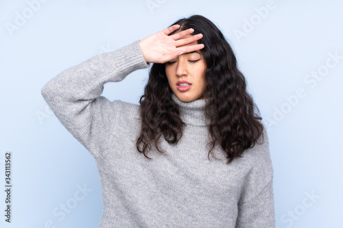 Spanish Chinese woman over isolated blue background with tired and sick expression