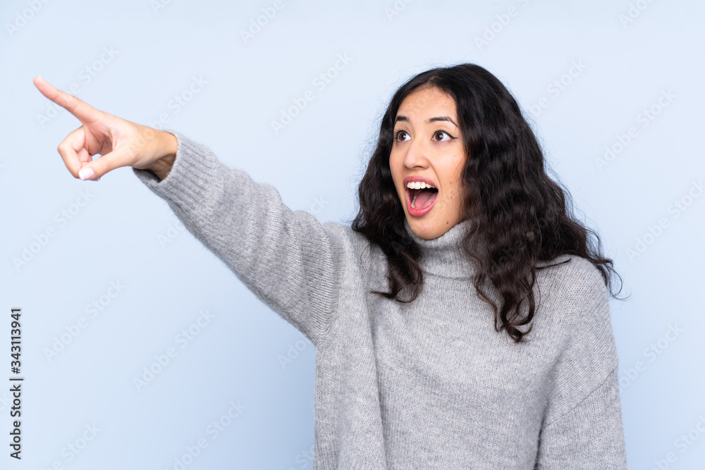 Spanish Chinese woman over isolated blue background pointing away Spanish Chinese woman over isolated blue background pointing away