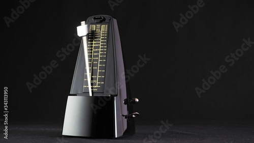 swinging metronome against a dark background