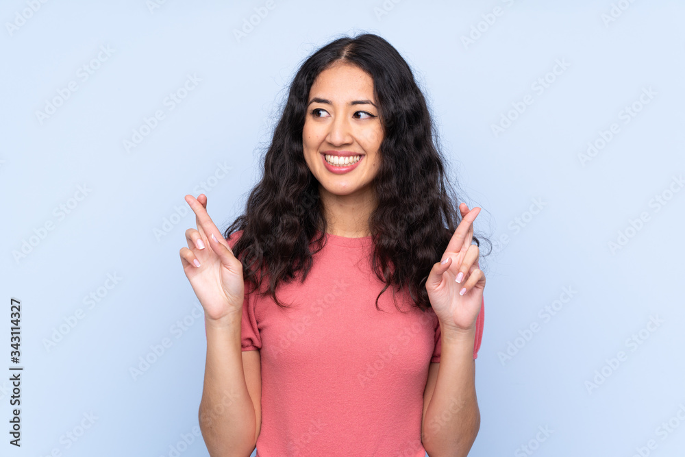 Mixed race woman wearing a sweater over isolated blue background with fingers crossing Mixed race woman wearing a sweater over isolated blue background with fingers crossing