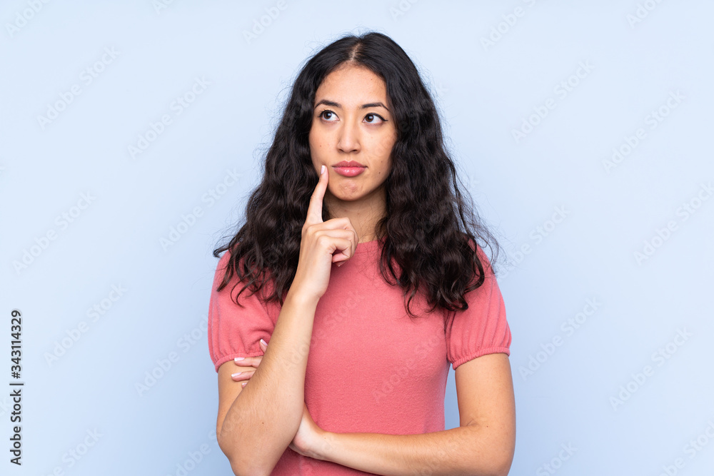 Mixed race woman wearing a sweater over isolated blue background thinking an idea Mixed race woman wearing a sweater over isolated blue background thinking an idea