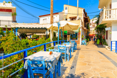 Tables with chairs in traditional Greek taverna on street of Kokkari town, Greece