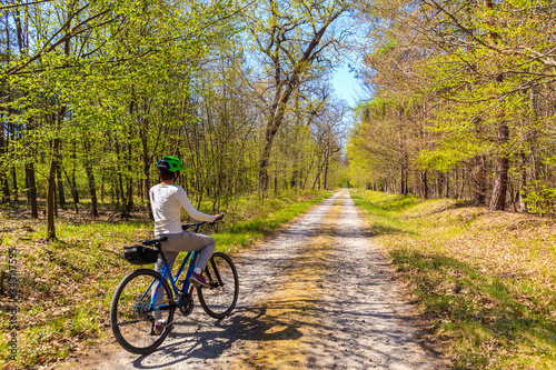 Young woman tourist cyclist on road in forest on sunny spring day in Puszcza Niepolomicka near Krakow city  Poland