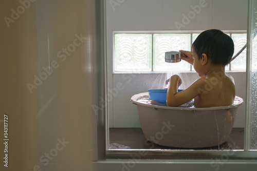 Asian boy showering and playing in water bucket