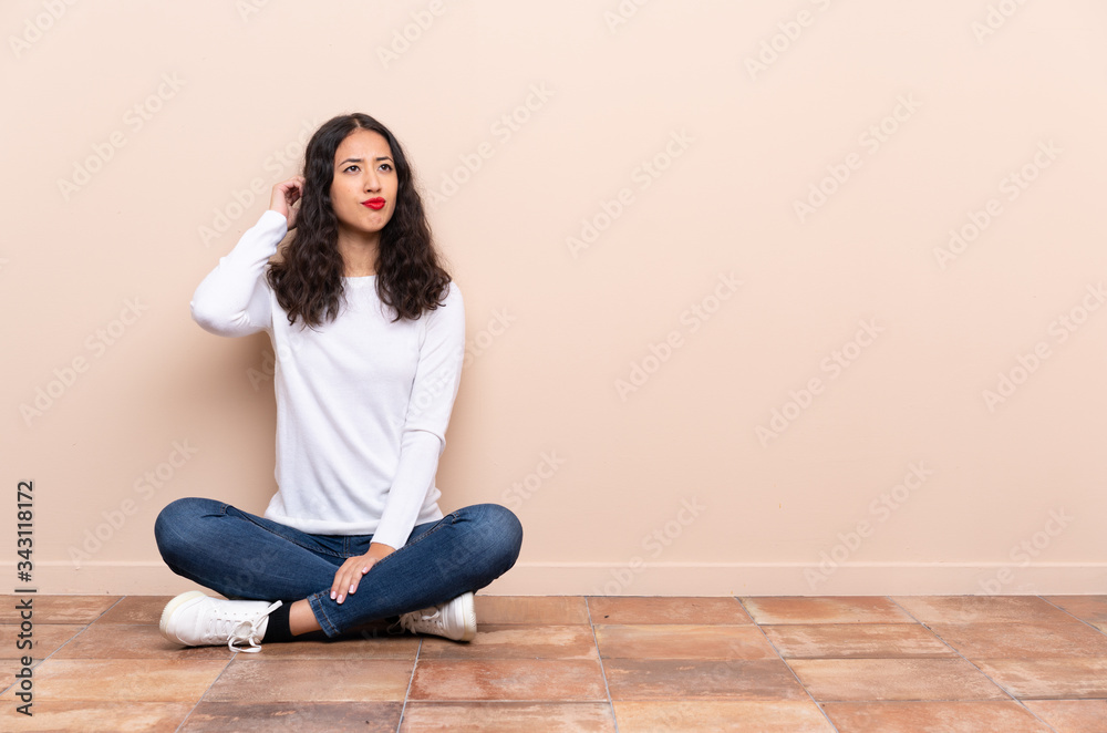 Young woman sitting on the floor having doubts