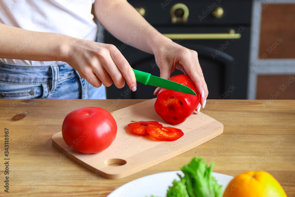 Slicing red pepper on salad, girl prepares salad at home in the kitchen Slicing red pepper on salad, girl prepares salad at home in the kitchen