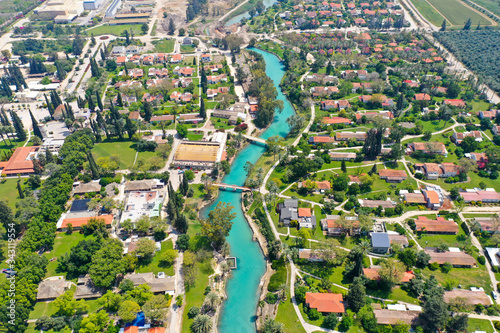 Aerial image of Kibbutz Nir David with Amal river channel turquoise water dividing east and west side riverside houses and palm trees, Israel. photo