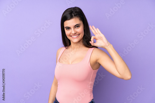 Young woman over isolated purple background showing ok sign with fingers