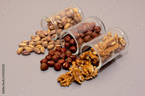 different nuts - hazelnut, walnut and pistachio nut. in glass box on light background photo