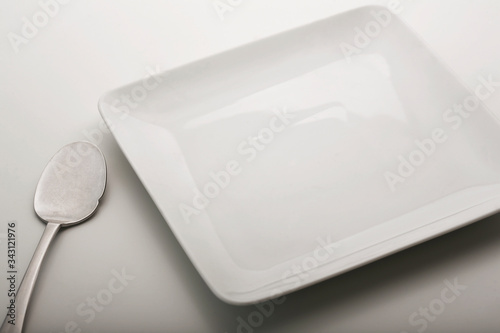 piatto bianco vuoto in porcellana  con cucchiaio isolato su sfondo bianco  photo
