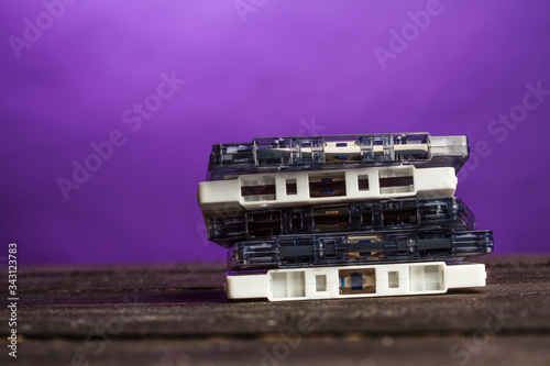 vecchie cassette musicali esposte una sopra l'altra su un tavolo di legno, isolate su sfondo viola