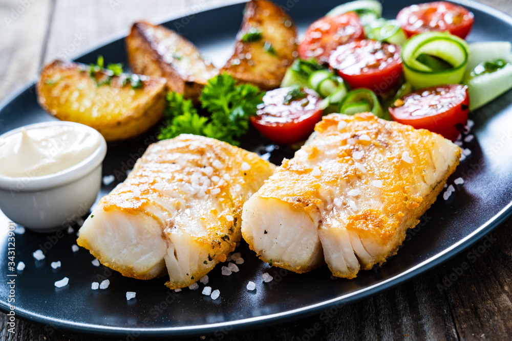 Fish dish - fried cod fillet with vegetables on wooden table
Fish dish - fried cod fillet with vegetables on wooden table
