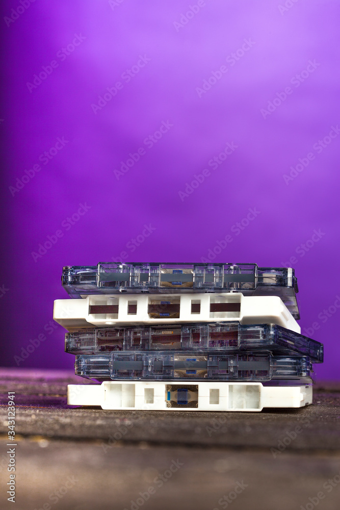 vecchie cassette musicali esposte una sopra l'altra su un tavolo di legno, isolate su sfondo viola vecchie cassette musicali esposte una sopra l'altra su un tavolo di legno, isolate su sfondo viola