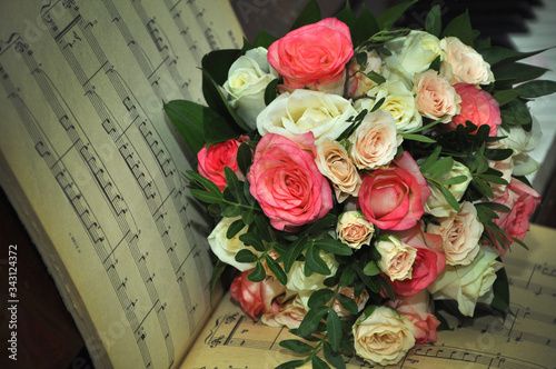 A bouquet of flowers lies on the old open notes on the piano