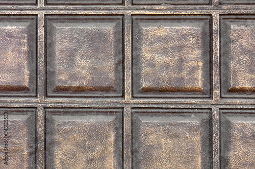 The texture of the concrete wall under the stylization of bronze metal squares.