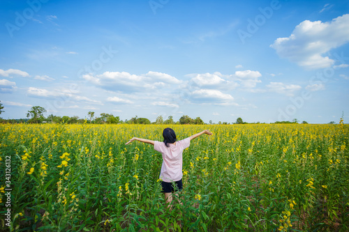 back view of young woman standing in hemp flowers field.