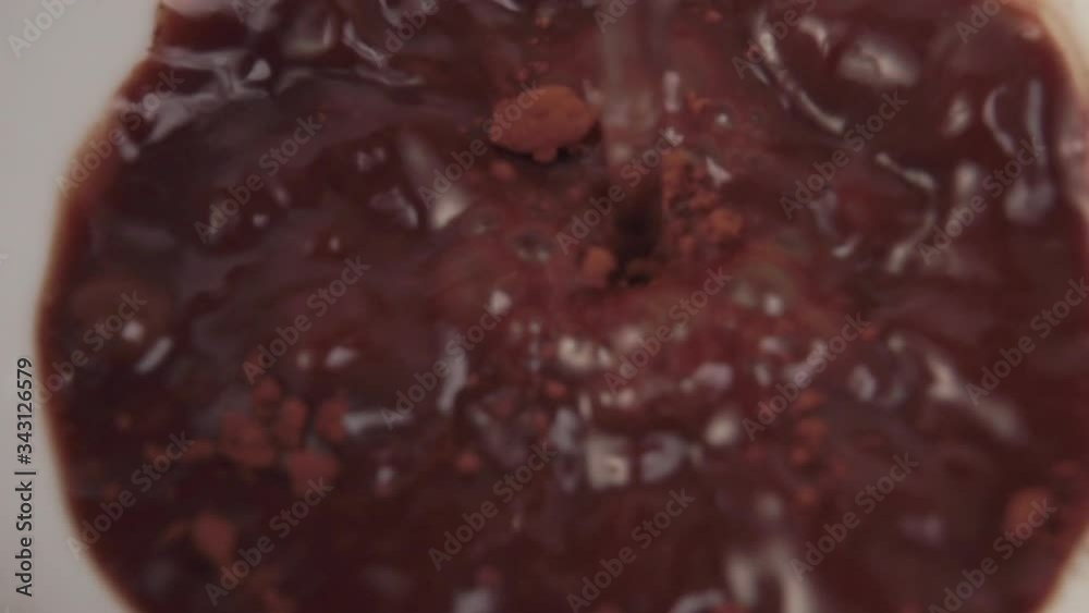 hot stream of water is poured into a white mug with cocoa powder. Instant nutritious breakfast drink. Close-up. Macro shot