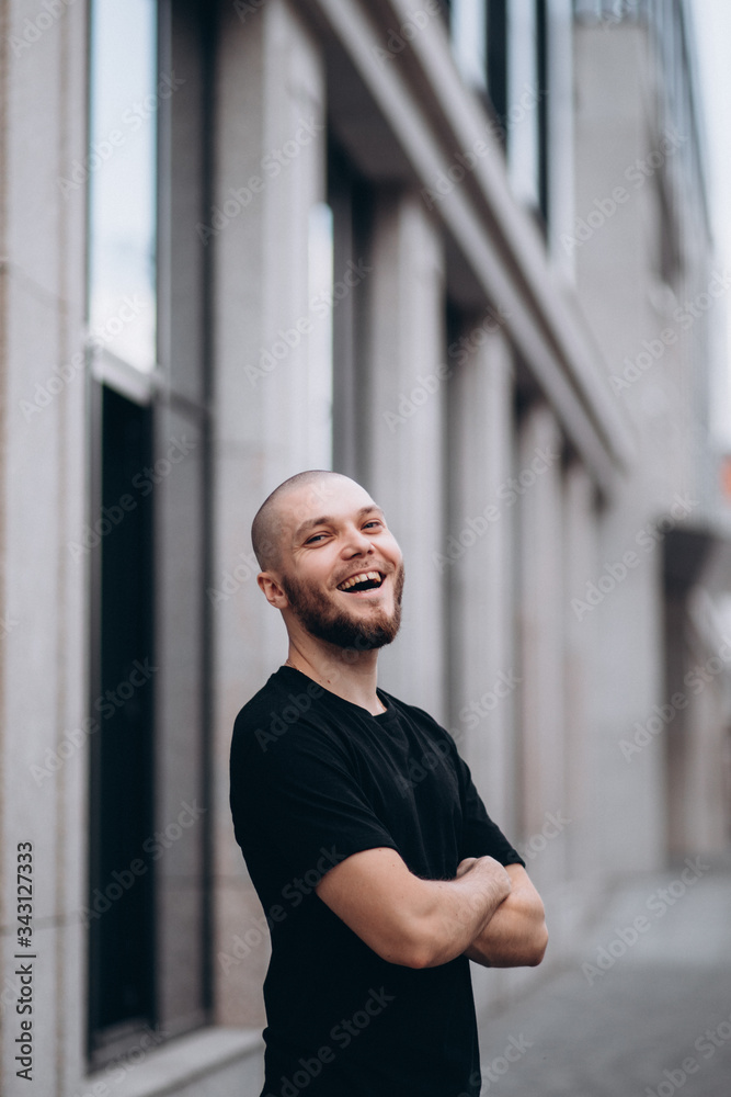 portrait of a bald happy bearded man in a black t-shirt on the street who is looking at the camera portrait of a bald happy bearded man in a black t-shirt on the street who is looking at the camera