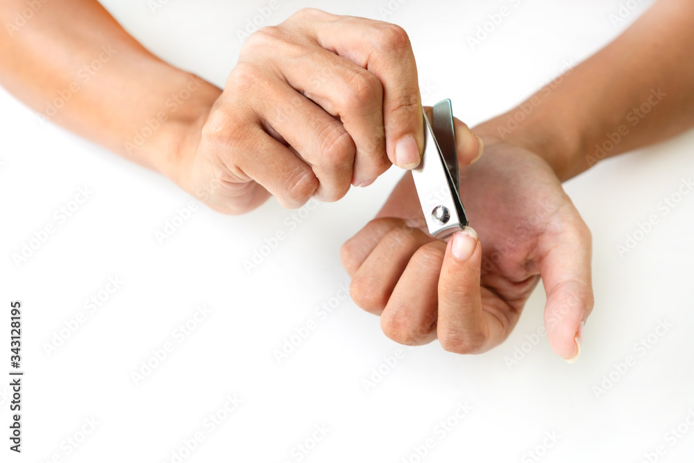 Closeup of a woman cutting nails, using nail clipper, health care concept.
