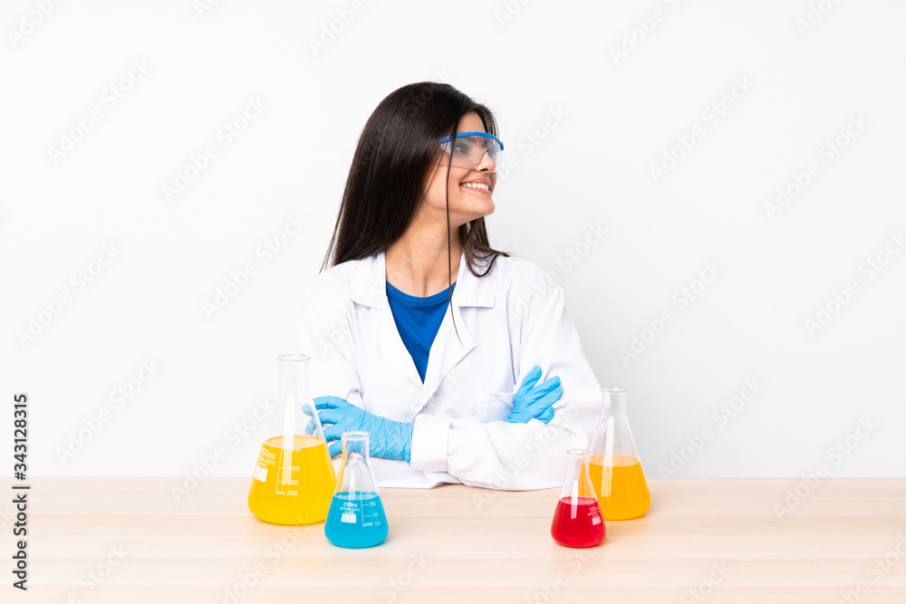 Young scientific woman in a table with arms crossed and happy Young scientific woman in a table with arms crossed and happy