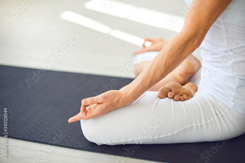 Close up of yoga woman hand sitting relaxation in lotus field on floor in studio class.
