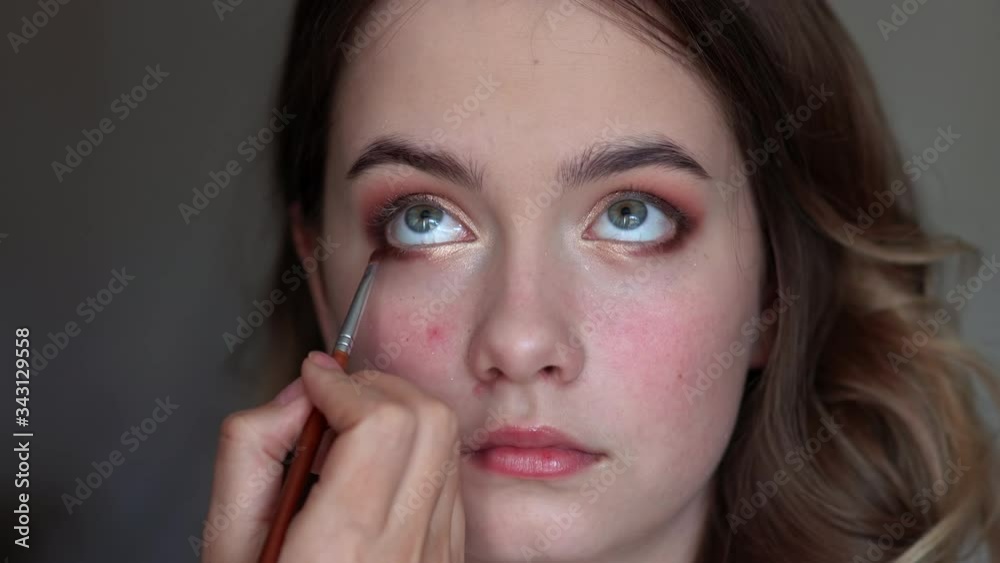 Girl makeup artist paints the eyes of a young girl Girl makeup artist paints the eyes of a young girl