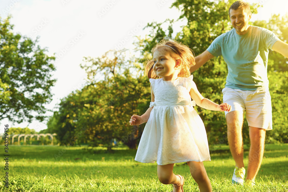 Father's day. Father running plays with his daughter on the grass in the summer park on a sunny day. Father's day. Father running plays with his daughter on the grass in the summer park on a sunny day.