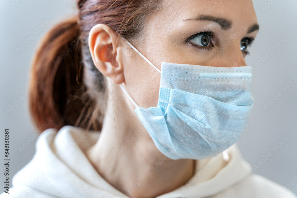 Portrait of sexy woman with red hair in medical mask close-up in studio. Girl in medical mask against viruses and infections. Coronavirus 2019-ncov covid-19 concept.