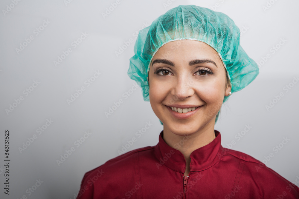 Dottoressa con cuffietta verde e camice rosso è sorridente e positiva, isolata su sfondo bianco Dottoressa con cuffietta verde e camice rosso è sorridente e positiva, isolata su sfondo bianco