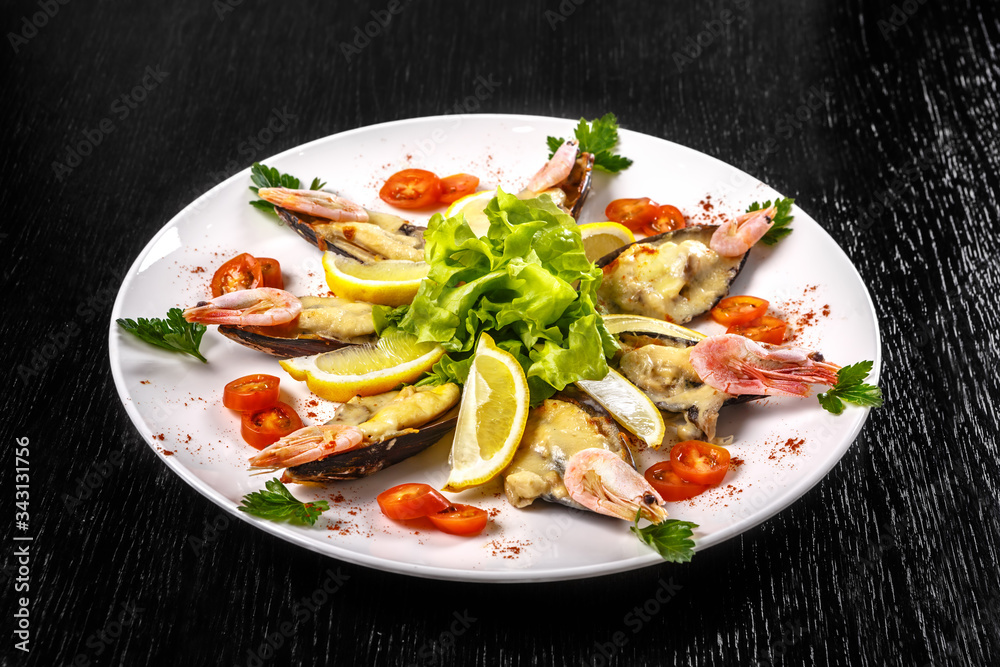Shrimps, tomatoes and lemon are beautifully laid out on a dish on a black background. Shrimps, tomatoes and lemon are beautifully laid out on a dish on a black background.