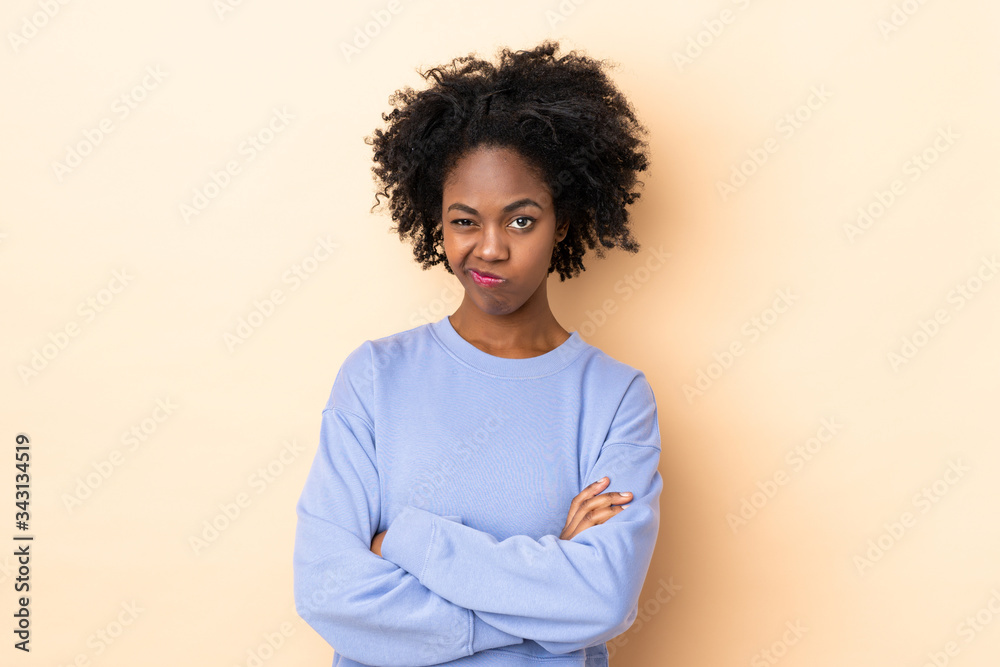 Young African American woman isolated on beige background with unhappy expression Young African American woman isolated on beige background with unhappy expression