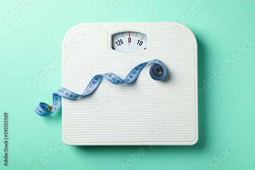 Scales and measuring tape on mint background. Weight loss concept