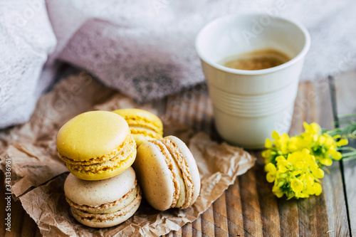 Macarons saveur vanille et citron avec une tasse de café chaud sur une table en bois
