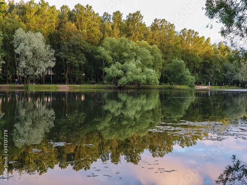 Wallpaper Mural Yaroslavl. Warm evening in Neftyanik Park. Park refinery. Reflection of colorful sunset in the lake. Peace and quiet surrounded by green trees Torontodigital.ca
