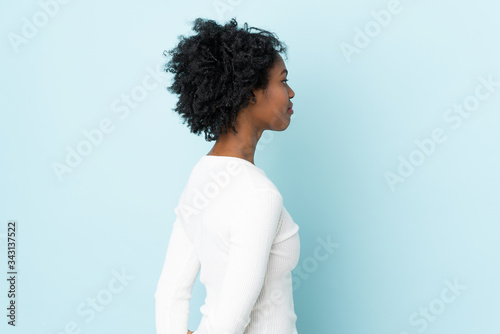 Young African American woman isolated on blue background in back position and looking back
