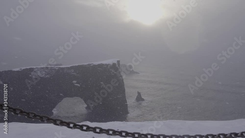 Dyrhólaey is a small peninsula with striking views, a lighthouse and a large arch of volcanic rock at sea during the cold Icelandic ridicule. Snowfall.