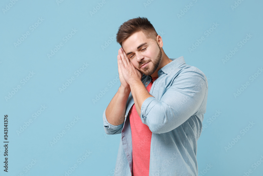 Relaxed young bearded guy in casual shirt posing isolated on pastel blue background studio portrait. People sincere emotions lifestyle concept. Mock up copy space. Sleep with folded hands under cheek. Relaxed young bearded guy in casual shirt posing isolated on pastel blue background studio portrait. People sincere emotions lifestyle concept. Mock up copy space. Sleep with folded hands under cheek.