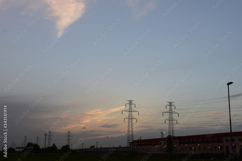 A series of high transmission lines next to a long factory building