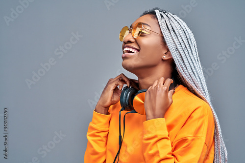 Close up side view portrait of afro american woman with sunglasses listening to music on earphones photo