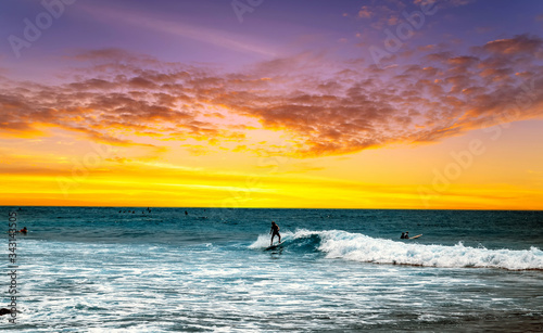 Silhouette Surfer Blue Ocean Wave Sunrise surfboard on a beach at sunset.
