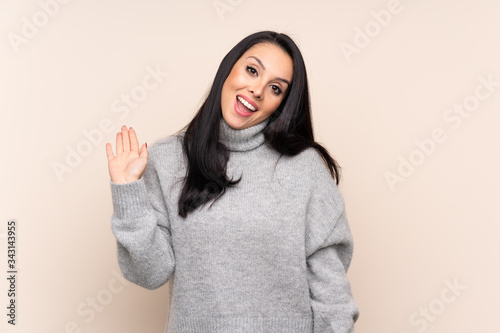 Young Colombian girl over isolated background saluting with hand with happy expression © luismolinero